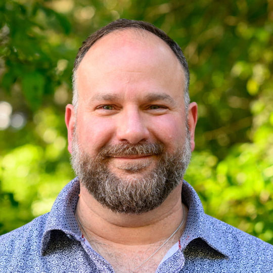 Headshot of a bearded white man in a floral shirt